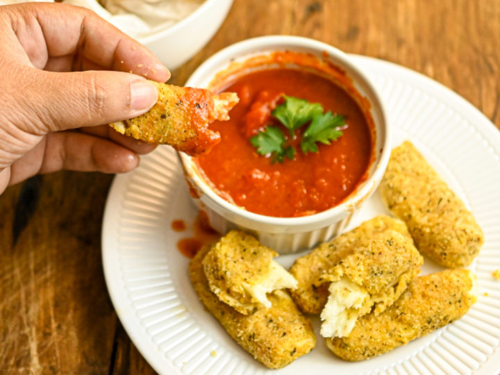 keto baked mozzarella cheese sticks dipped in marinara sauce