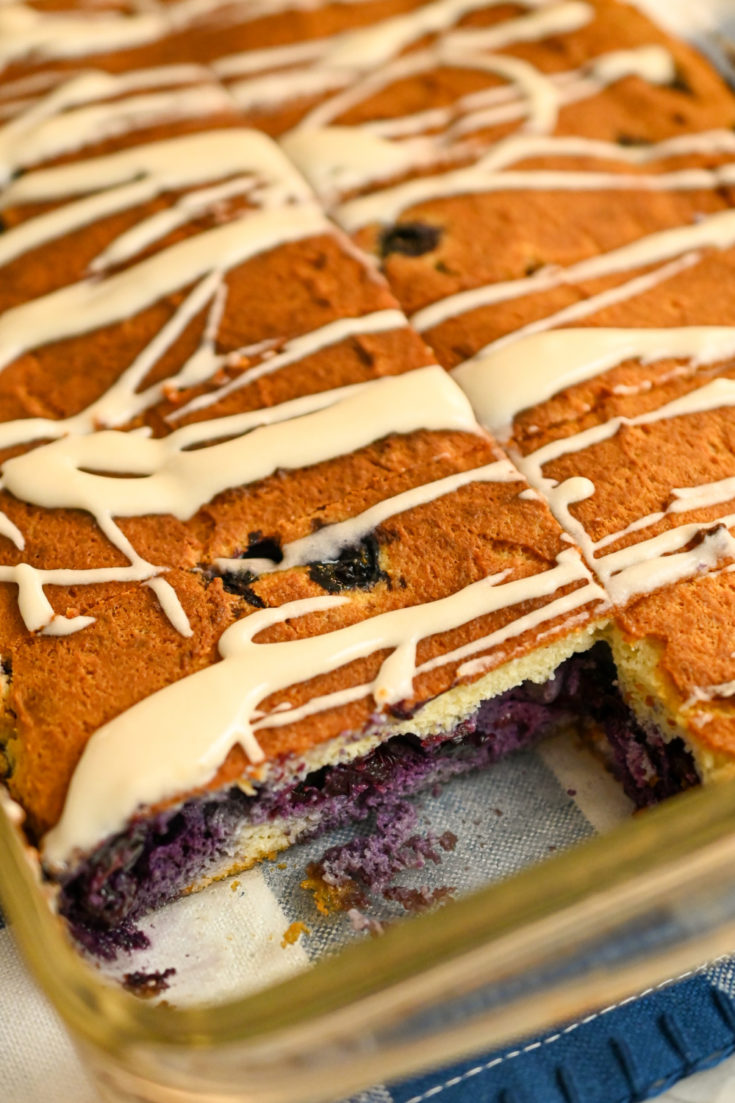 keto blueberry bars in clear rectangle baking pan with a sliced removed