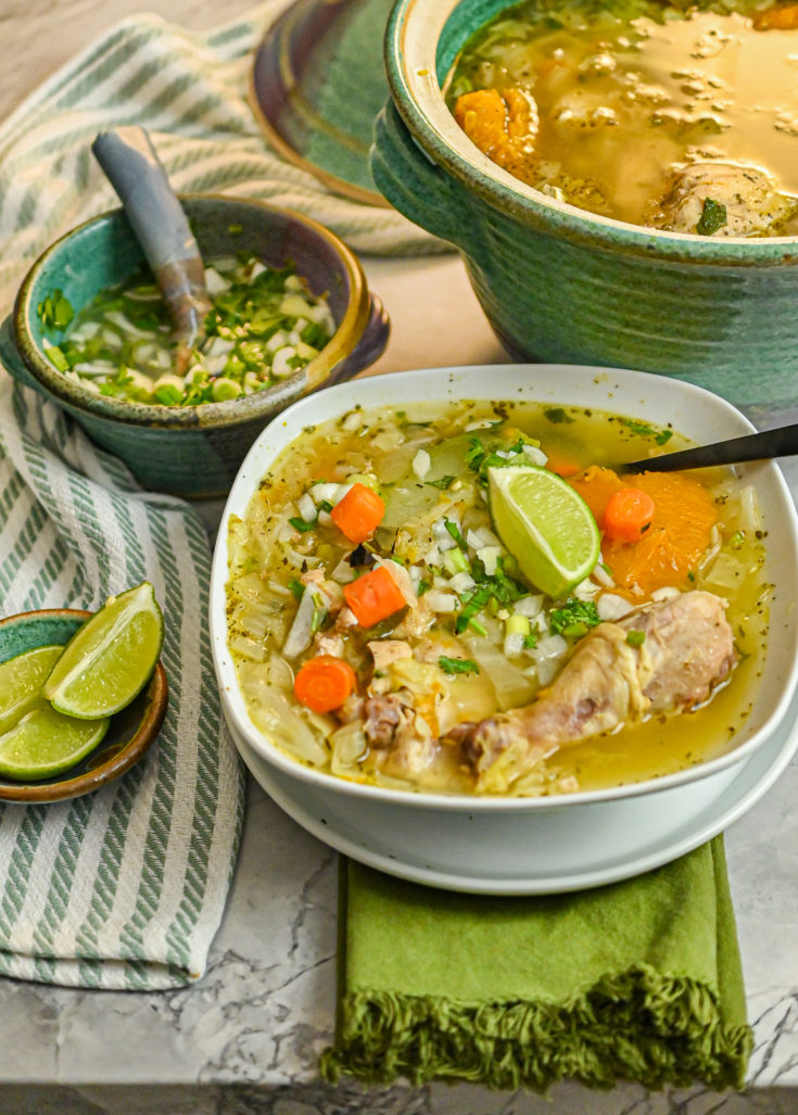 keto chicken soup served in white bowl with chilito and large pot of soup in background