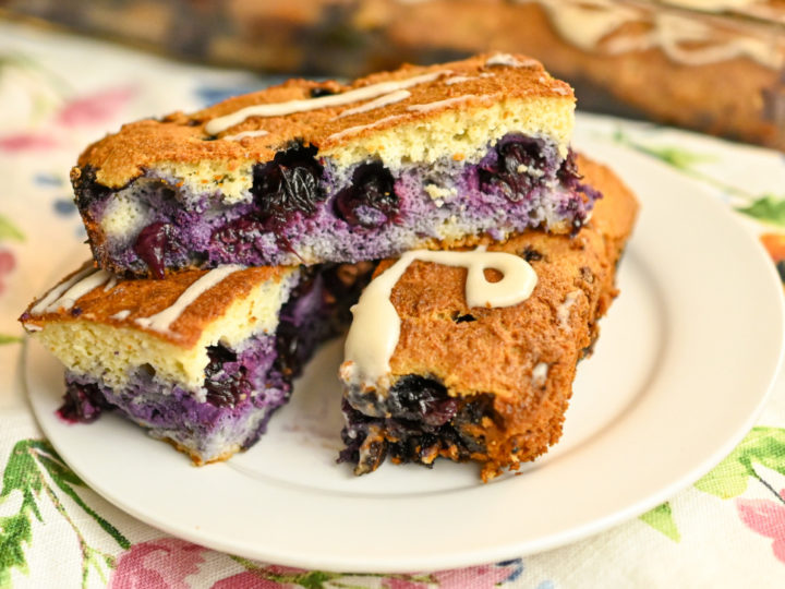 three keto blueberry bars stacked on a small white plate
