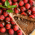close up image of keto chocolate raspberry cheesecake with a slice missing