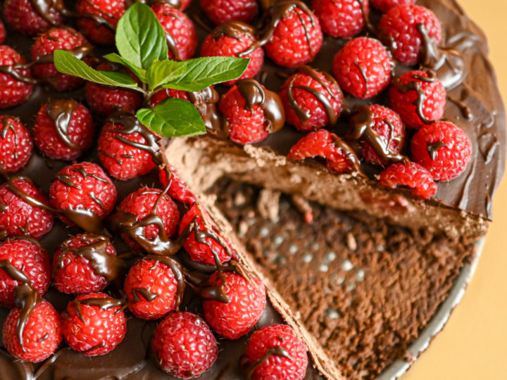 close up image of keto chocolate raspberry cheesecake with a slice missing