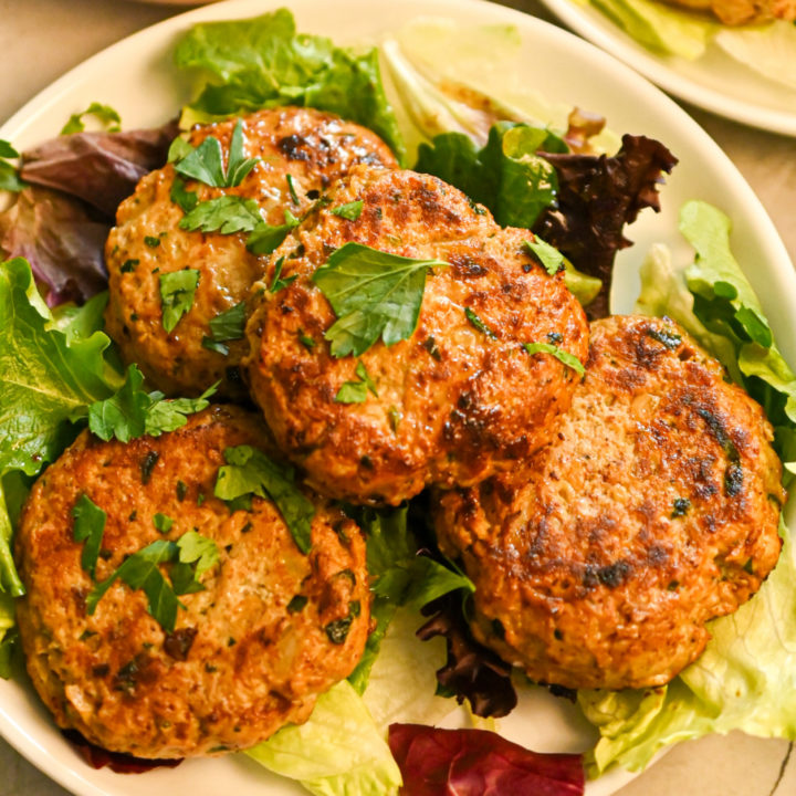 keto chicken burgers served on a bed of salad greens on a white plate