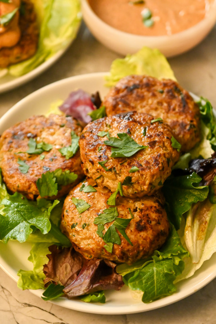 keto ground chicken burgers stacked on a bed of greens