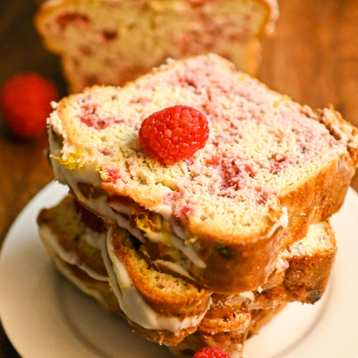keto raspberry bread slices stacked on a white plate