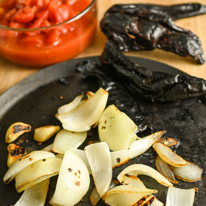 roasting dried peppers along with garlic and onion on a comal