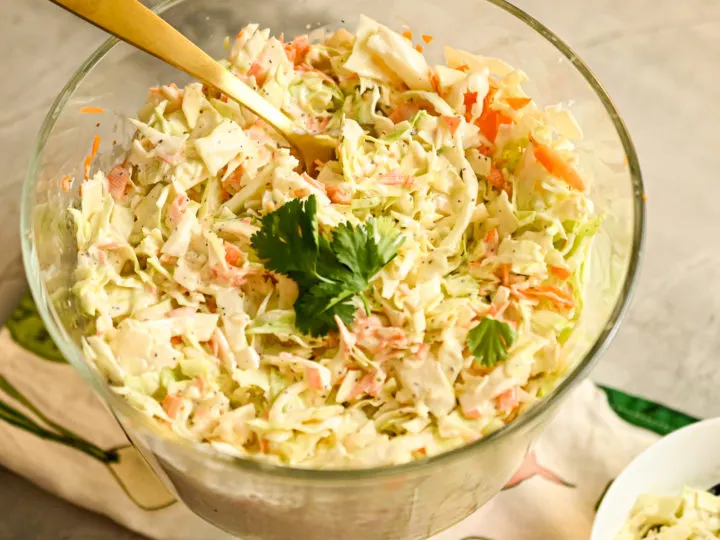 Keto Coleslaw served in a clear salad bowl with a gold serving spoon