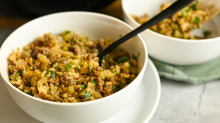 close up image of keto dirty rice served in a white bowl with a black fork