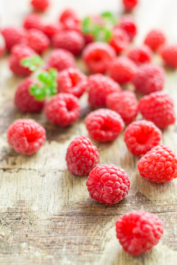 fresh raspberries scattered on a wooden board