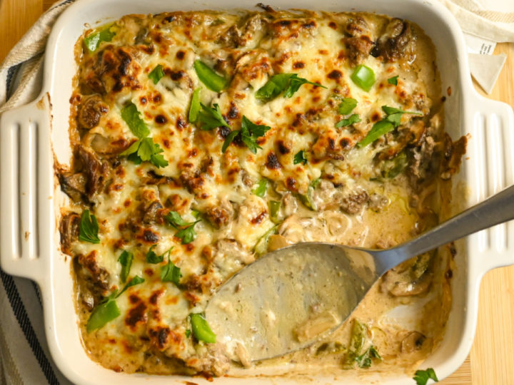 keto Philly cheesesteak casserole baked in a white square dish with some servings missing