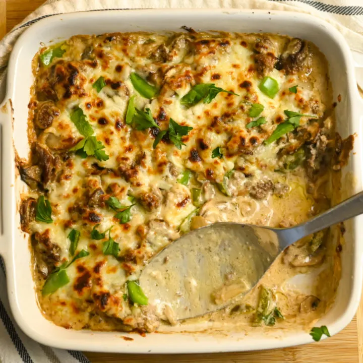 keto Philly cheesesteak casserole baked in a white square dish with some servings missing