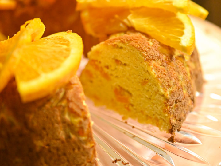 keto orange cake with slices missing garnished with slices of orange