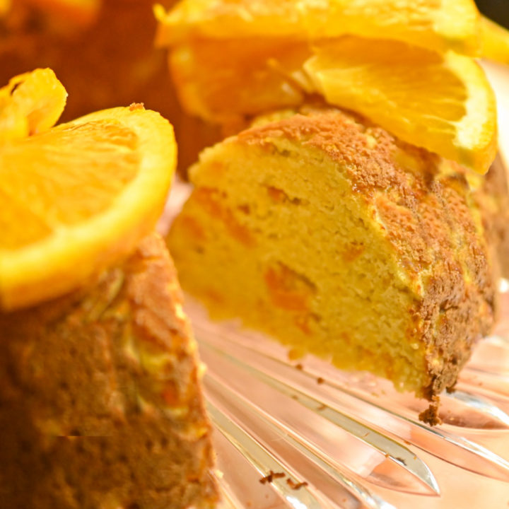 keto orange cake with slices missing garnished with slices of orange