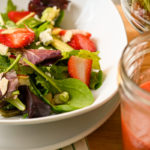 keto strawberry salad with strawberry vinaigrette in a mason jar next to it