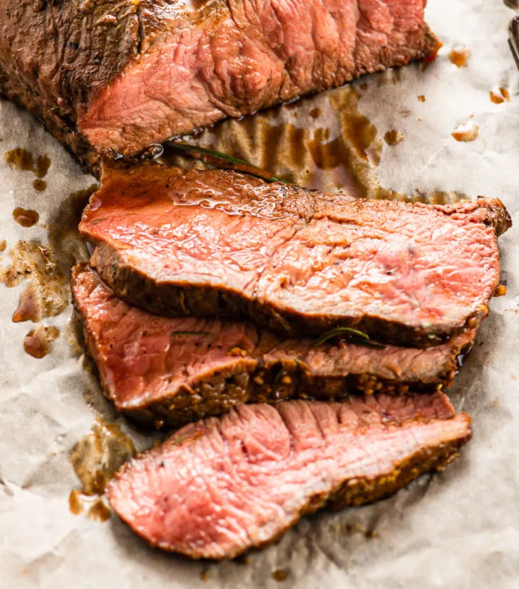 ribeye steak cooked and sliced after resting on parchment paper