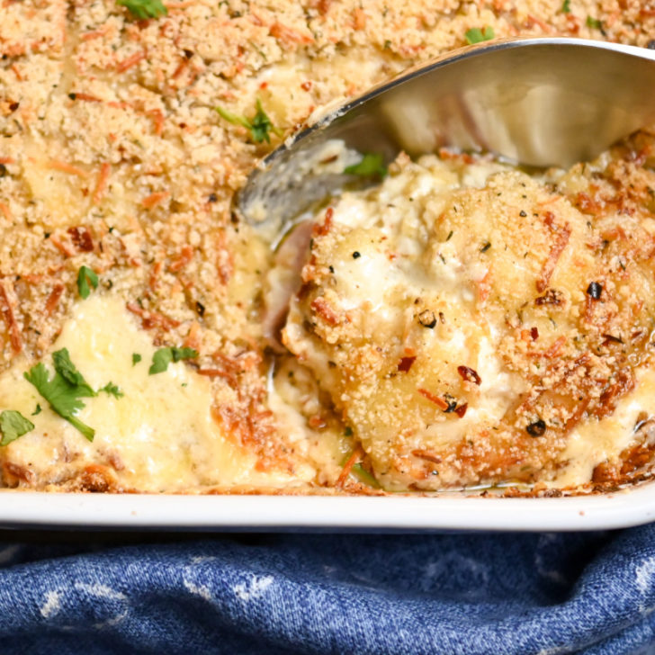 gluten-free cordon bleu lasagna served in a white dish with a blue kitchen towel underneath