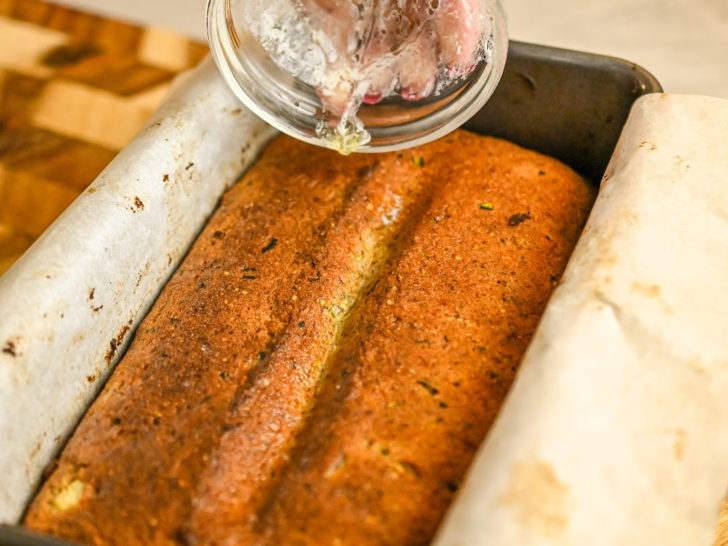 keto coconut flour zucchini bread backed and being drizzled with melted butter for more flavor