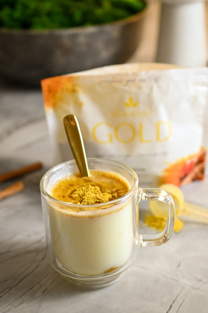 Instant golden milk supplement being mixed in hot water with heavy cream