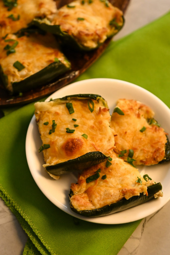 keto-friendly three cheese stuffed poblano peppers served as an appetizer on a wooden board