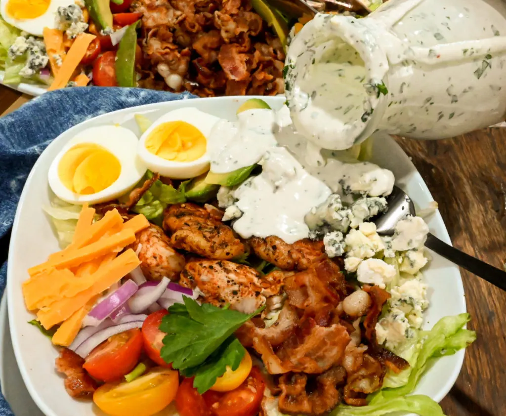 keto-friendly blue cheese dressing being poured over a keto Cobb salad