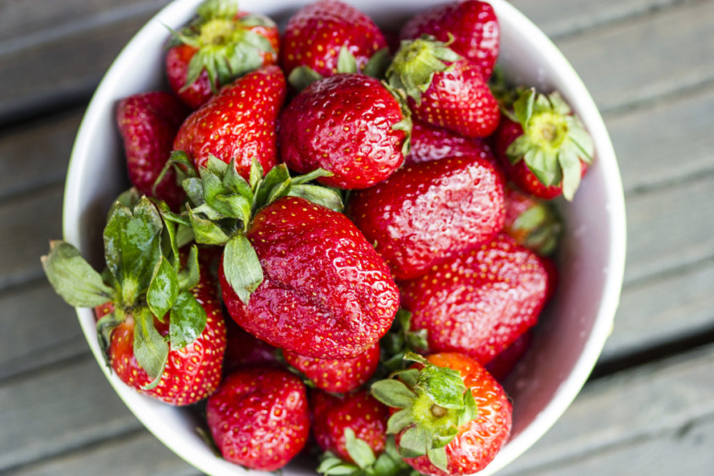 fresh whole strawberries in a white bowl