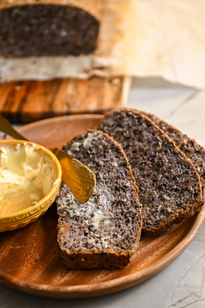 Low-carb pumpernickel bread sliced and served with a pat of butter