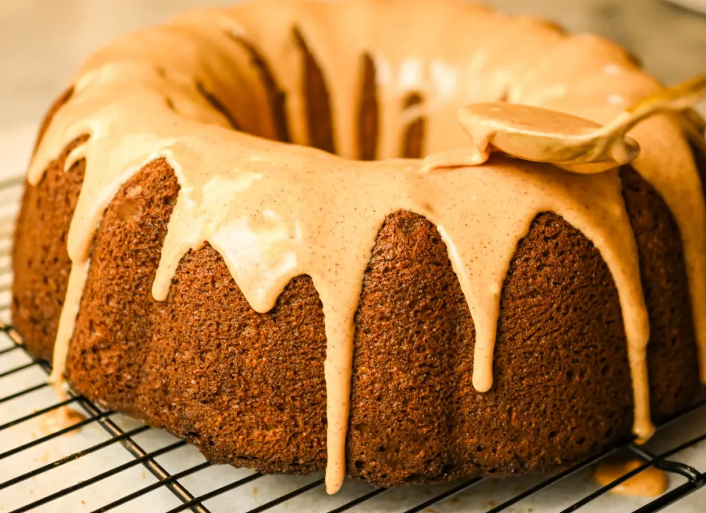 keto spice icing being added to a keto sour cream pumpkin cake