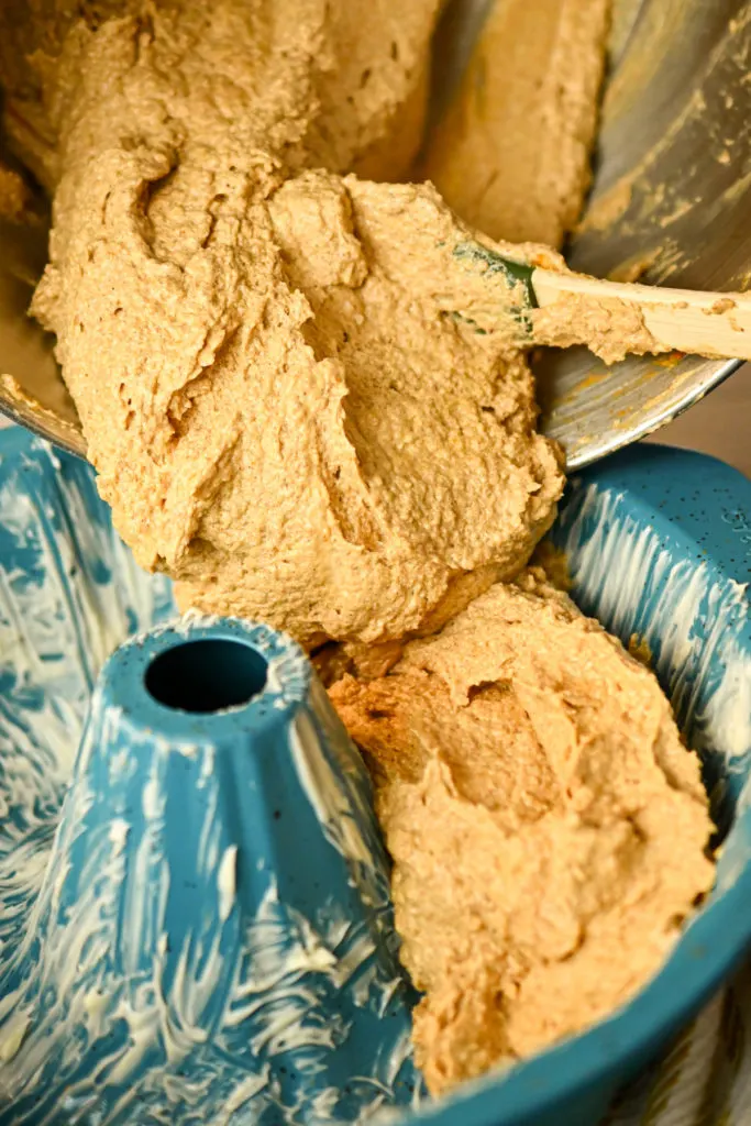 keto peanut butter cake batter being added to a bundt pan