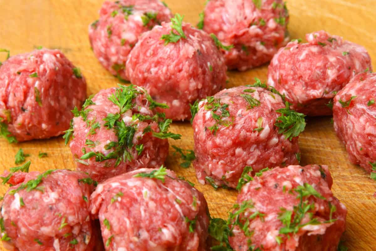 Raw meatballs on a wooden board