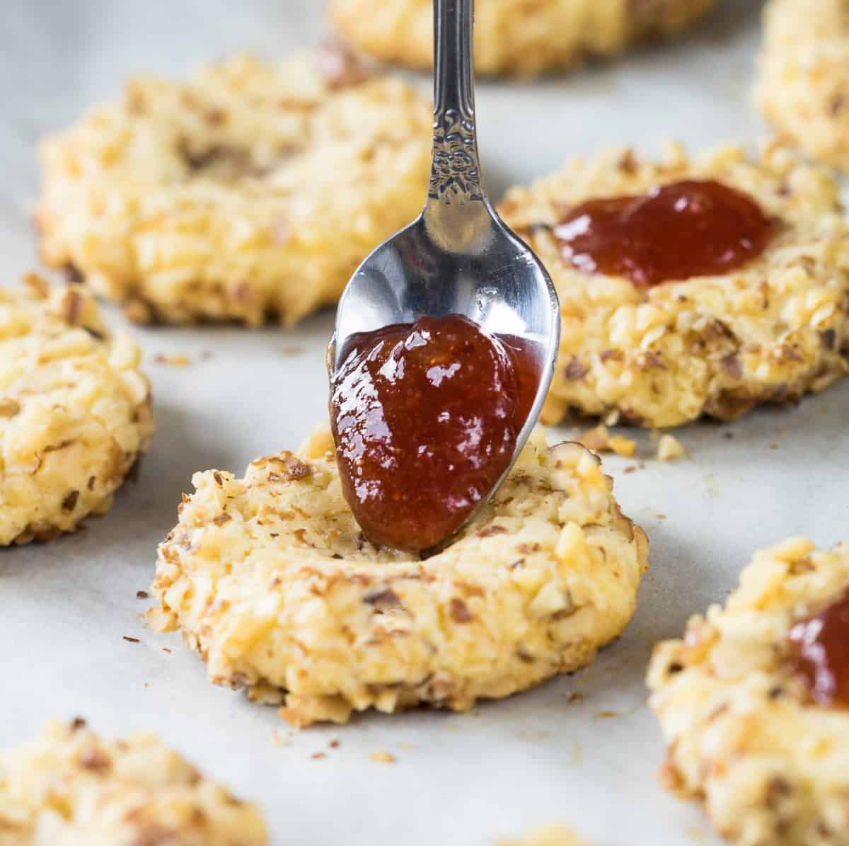 sugar-free strawberry jam being added to the keto peanut butter thumbprint cookies
