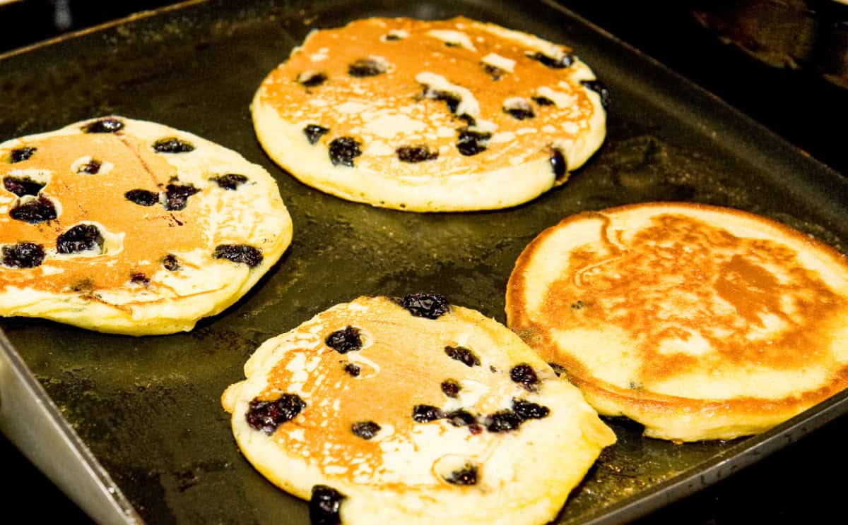 keto coconut flour blueberry pancakes cooked on a griddle