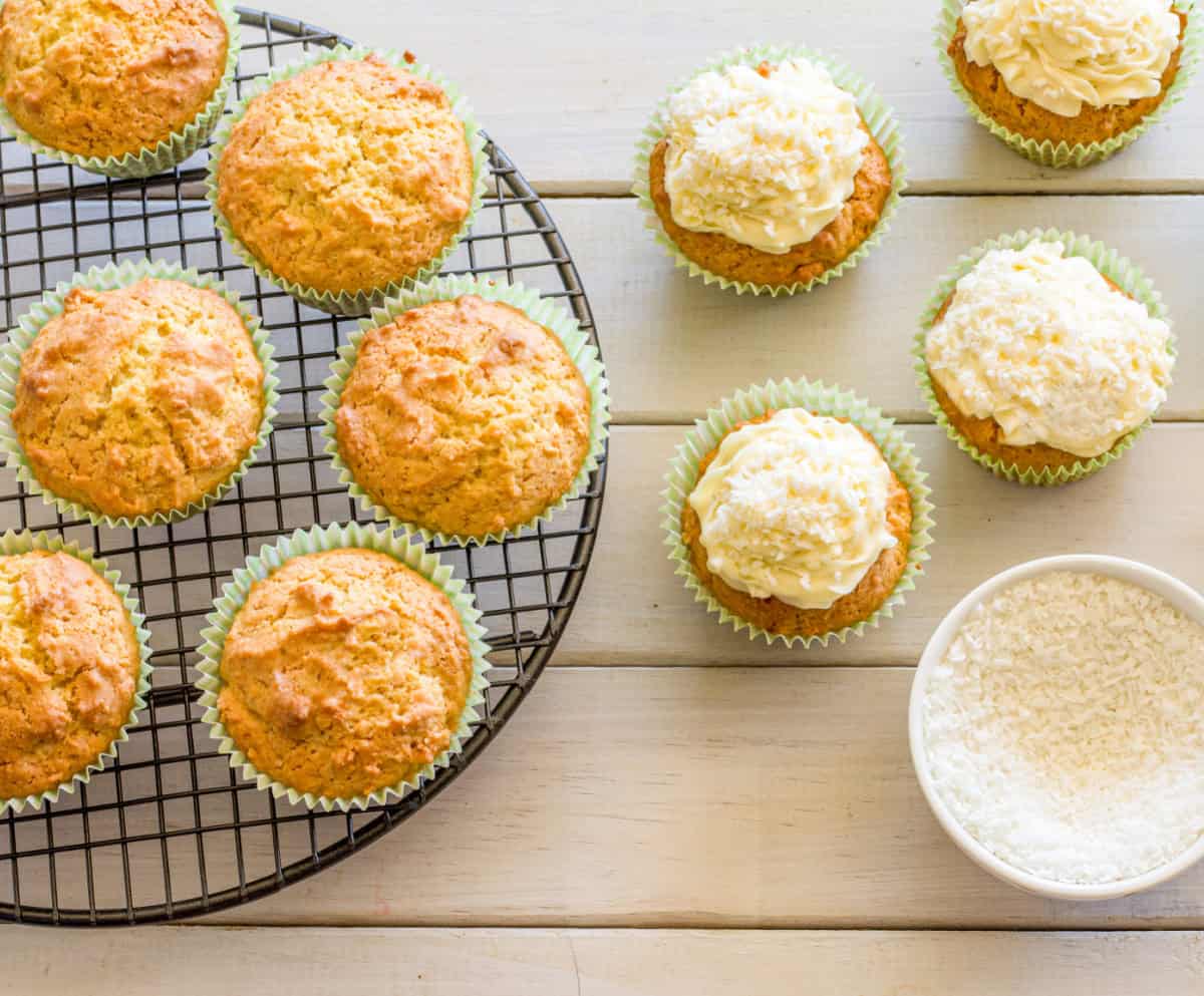 Keto Coconut Cupcakes Being Frosted And Topped With Sugar-Free Coconut Flakes